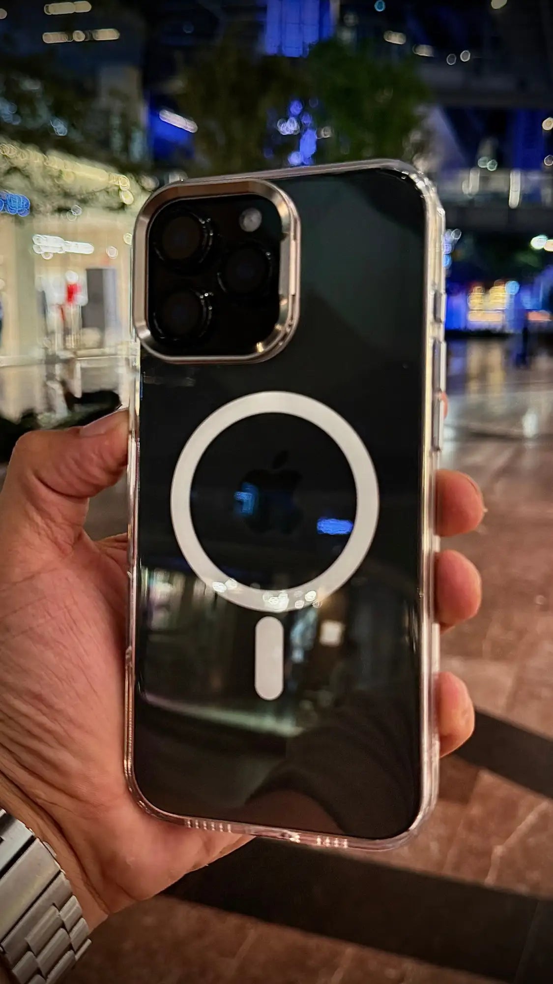 Funda de teléfono negra brillante con un anillo de carga magnética plateado y bordes transparentes.