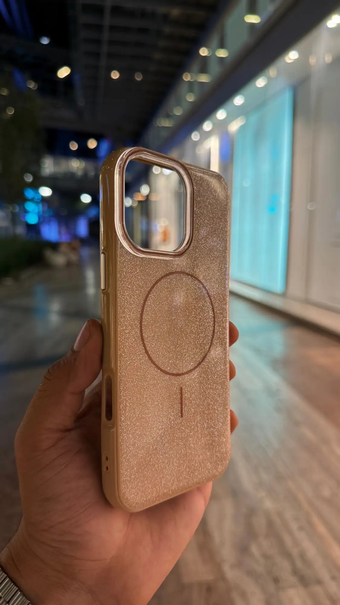 Una funda de teléfono con purpurina en oro rosa y diseño de almohadilla de carga magnética circular.