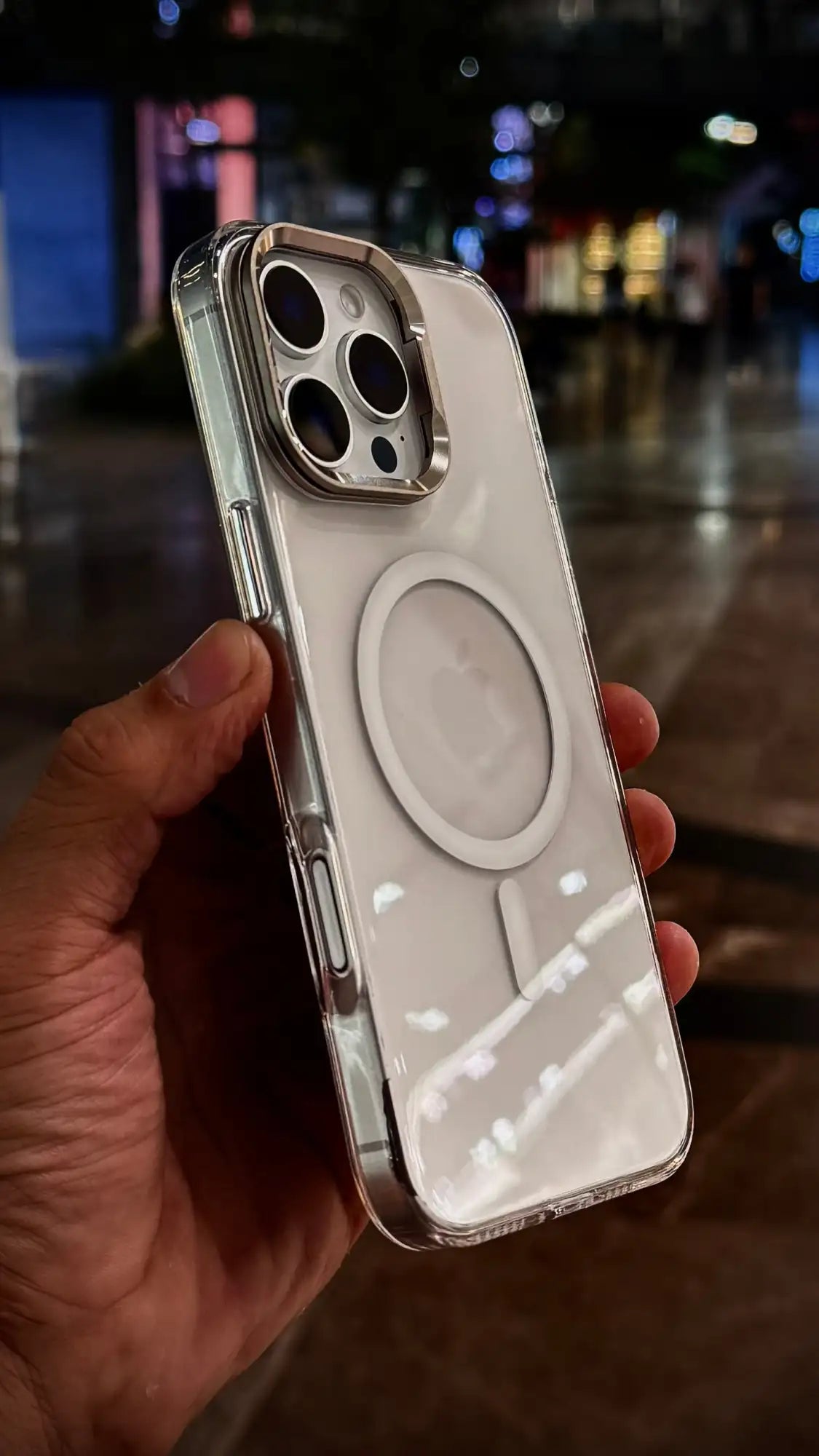 Funda protectora transparente con marco metálico plateado y almohadilla de carga MagSafe circular en la parte trasera.