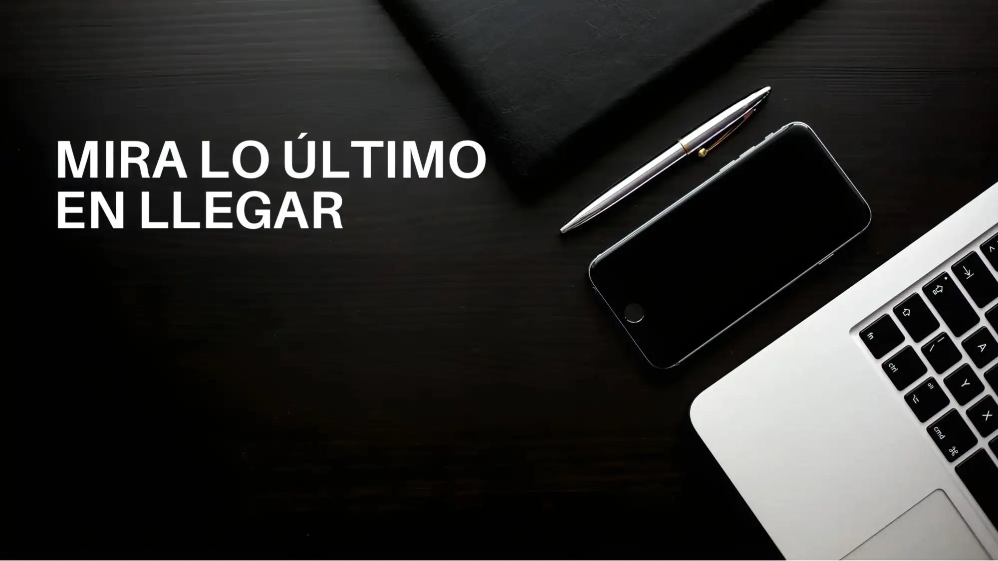 Pluma plateada con un acabado metálico elegante y un diseño minimalista, reposando junto a un smartphone negro sobre una superficie de madera oscura.